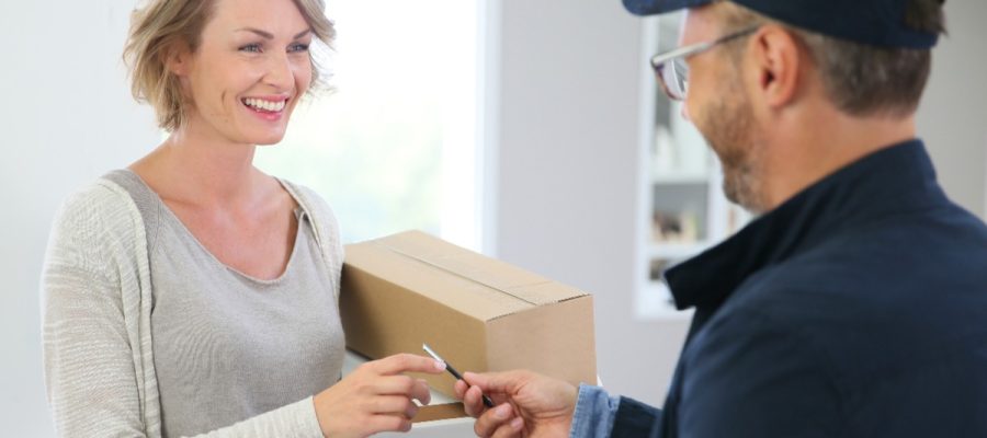 Paketbote übergibt einer Frau ein Paket. Beitrag: Verteilzeit im Homeoffice - Sind Paketboten Arbeitskollegen?